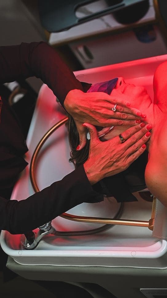 A specialist’s hands working through a neck and scalp massage at the basin